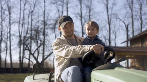 caucasian man driving a quad with his son in the countryside