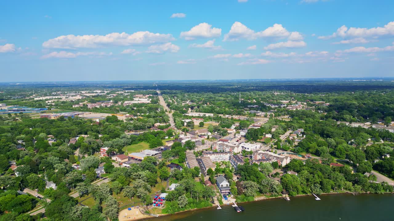 An aerial view of Lake Zurich, Illinois, featuring its waterfront, suburban homes, green trees, and a clear blue sky over the tranquil lake