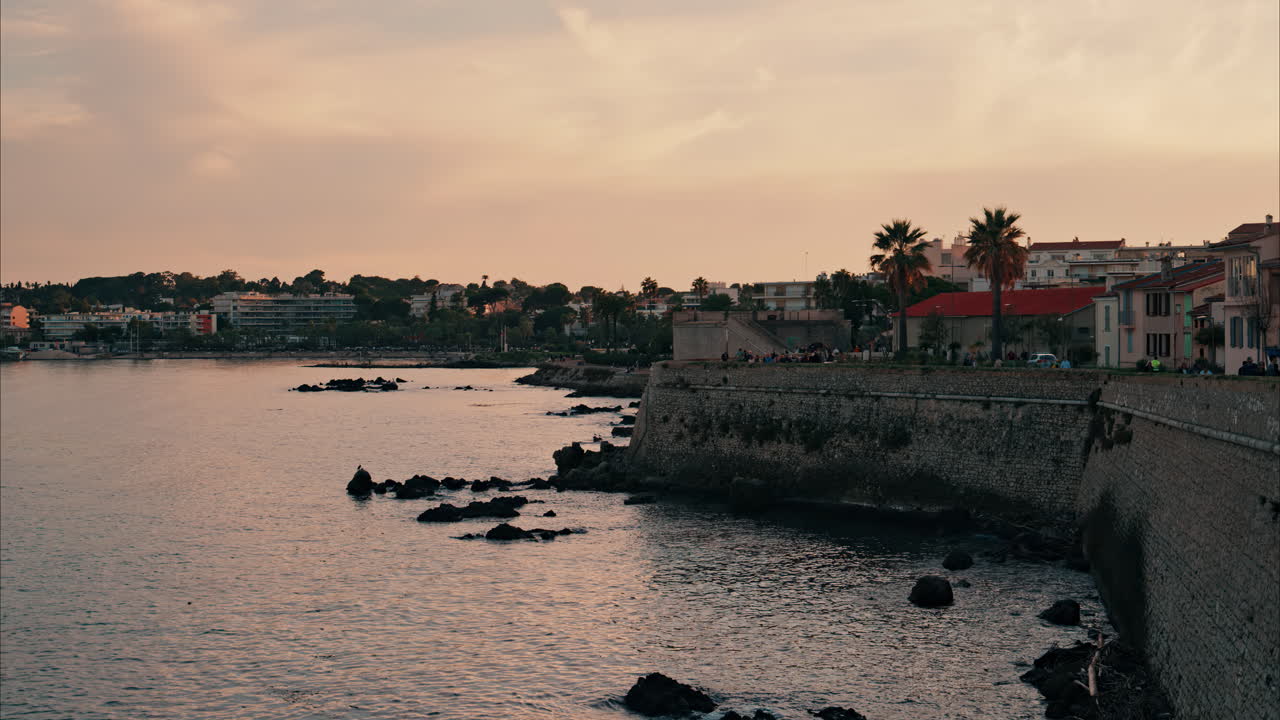 People walking on the coast in Antibes, France at sunset