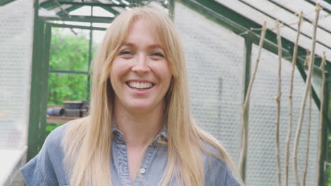 Portrait-Of-Smiling-Woman-Growing-Vegetables-Standing-In-Doorway-Of-Greenhouse