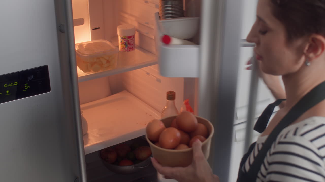 Woman in Apron Taking Eggs from Fridge