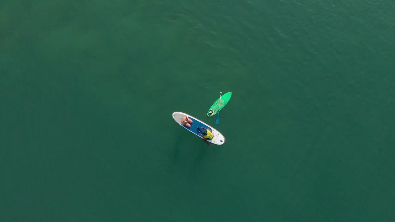 amigos disfrutando en el bote de remos junto con la tabla de surf en medio del mar
