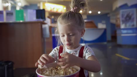 young girl eating popcorn in a movie theater