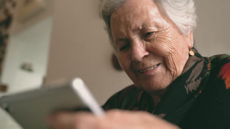 mujer de edad con gadget sentado en la mesa