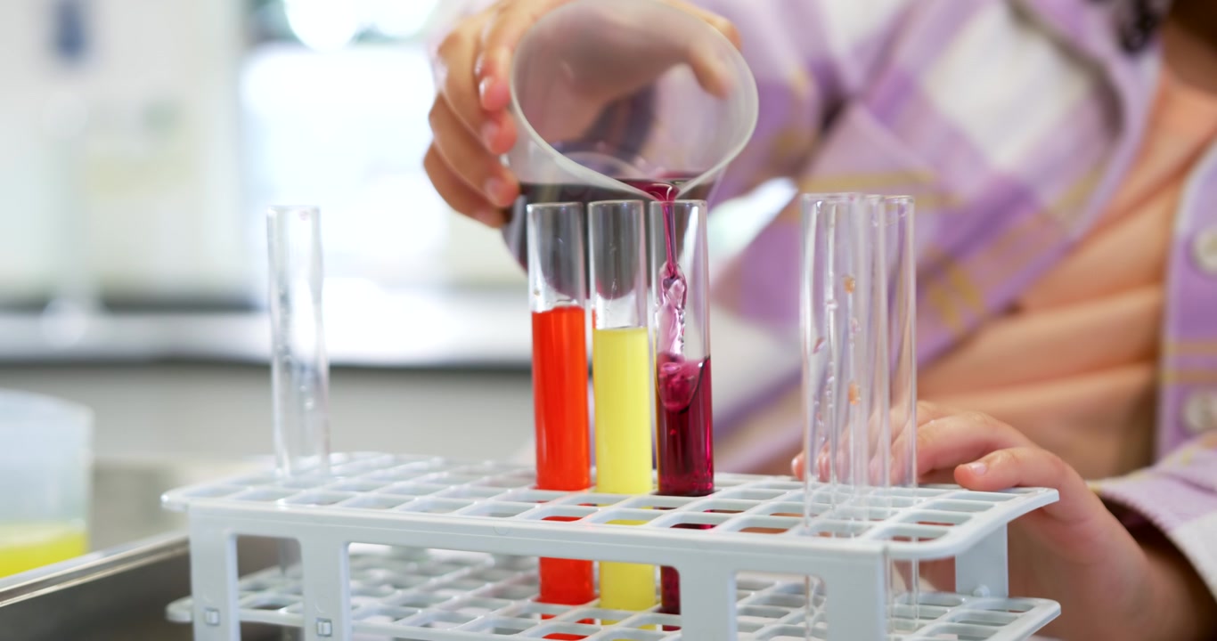 African female tipping beaker, pouring magenta into tube, steadying rack at lab bench checking fill