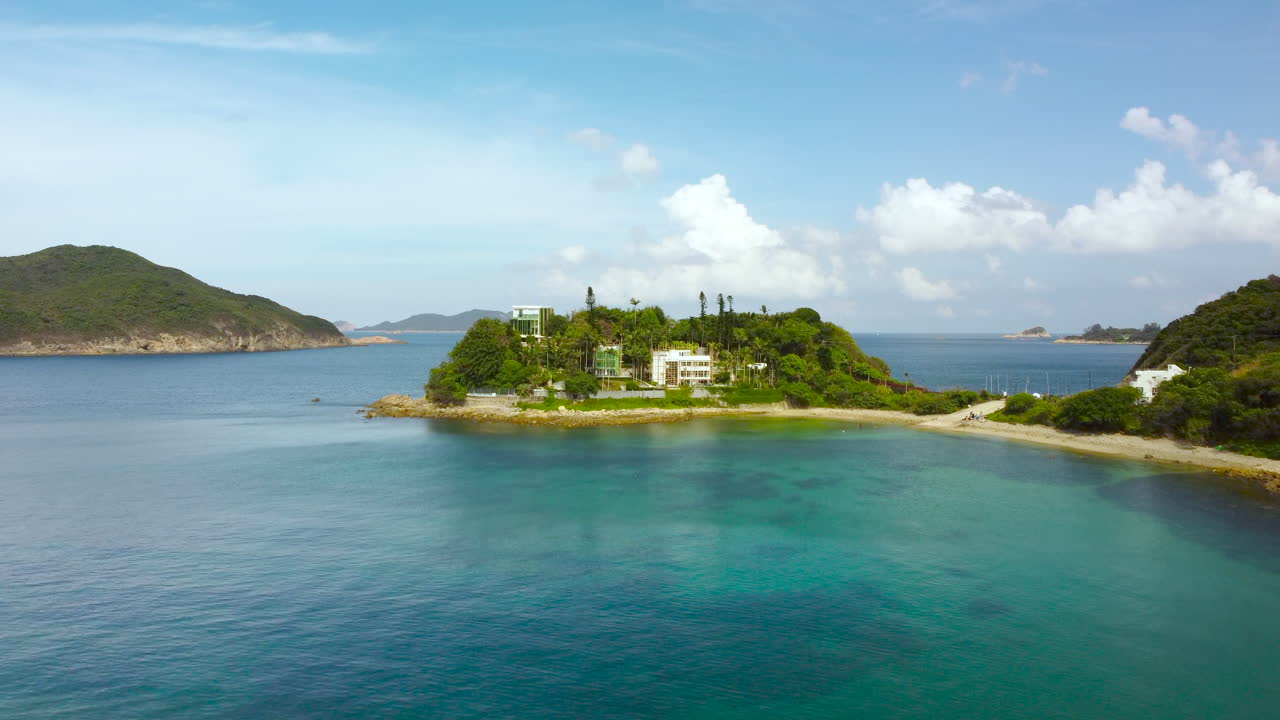 Aerial Drone dolly push in waves levitate over rock beach reveal island mansion. Sea waves on beautiful beach aerial view drone 4k shot. Isolated Hong Kong Sai Kung rural village mansion top view.