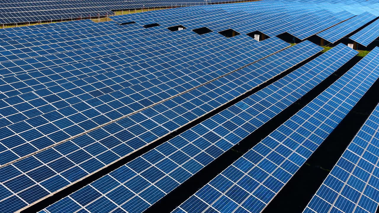 Veduta in prospettiva di una schiera di pannelli solari fotovoltaici blu. Ripresa aerea dall'alto di file di pannelli solari blu che si estendono attraverso il paesaggio rurale.