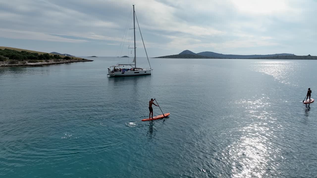 Standup Paddleboarding In The Sea Near The Yacht. - aerial shot