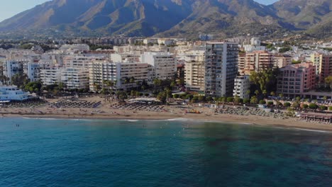 Disparo-De-Un-Dron-Alejándose-De-La-Playa-Sobre-El-Mar-Y-Alterando-El-Movimiento-Hacia-Los-Lados