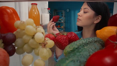 woman looking inside a refrigerator filled with fresh fruits and vegetables