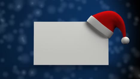 Weihnachtsmütze-über-Einem-Leeren-Plakat-Gegen-Schneeflocken,-Die-Auf-Blauen-Hintergrund-Fallen
