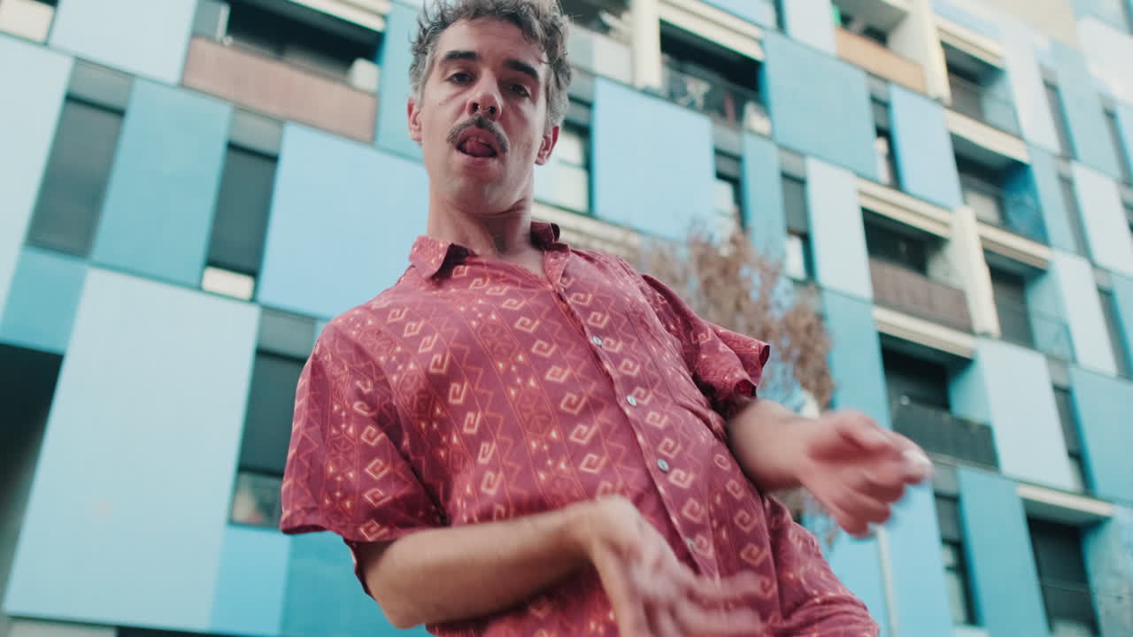 Expressive Man with Mustache Dancing in Urban Setting