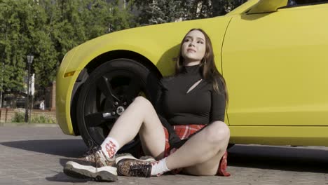 young woman relaxing by yellow sports car