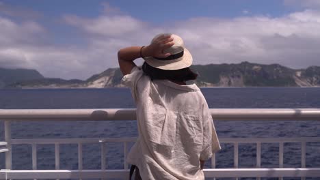 Mädchen-In-Abenteuerlichem,-Sommerlichem-Outfit,-Das-Auf-Einem-Schiff-Steht-Und-Auf-Das-Meer-Und-Die-Inseln-Blickt