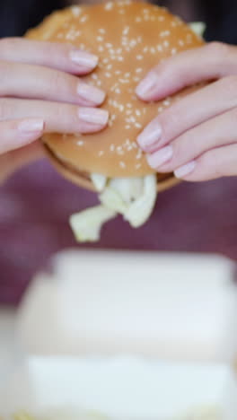 A woman eats a big burger at a fast food restaurant Vertical video