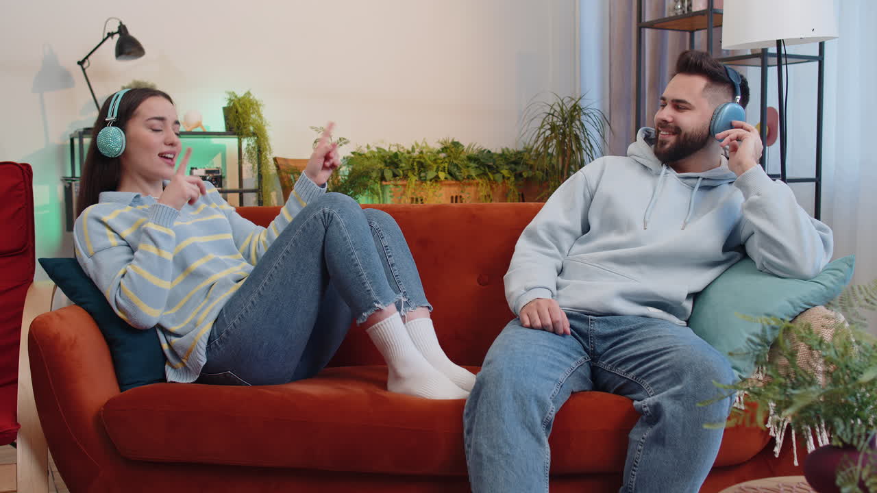 가족 남자 여자 무선 헤드폰 춤추고 집 소파에서 좋아하는 록 앤 롤 음악을 듣고