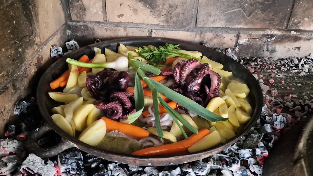 Octopus with vegetables slowly cooking under traditional iron bell lid