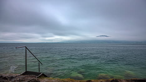 Paisaje-De-Agua-De-Lapso-De-Tiempo-En-El-Lago-Attersee-Austria-Movimiento-De-Nubes-Tormentosas-Con-Escaleras-Bajando-Por-La-Costa