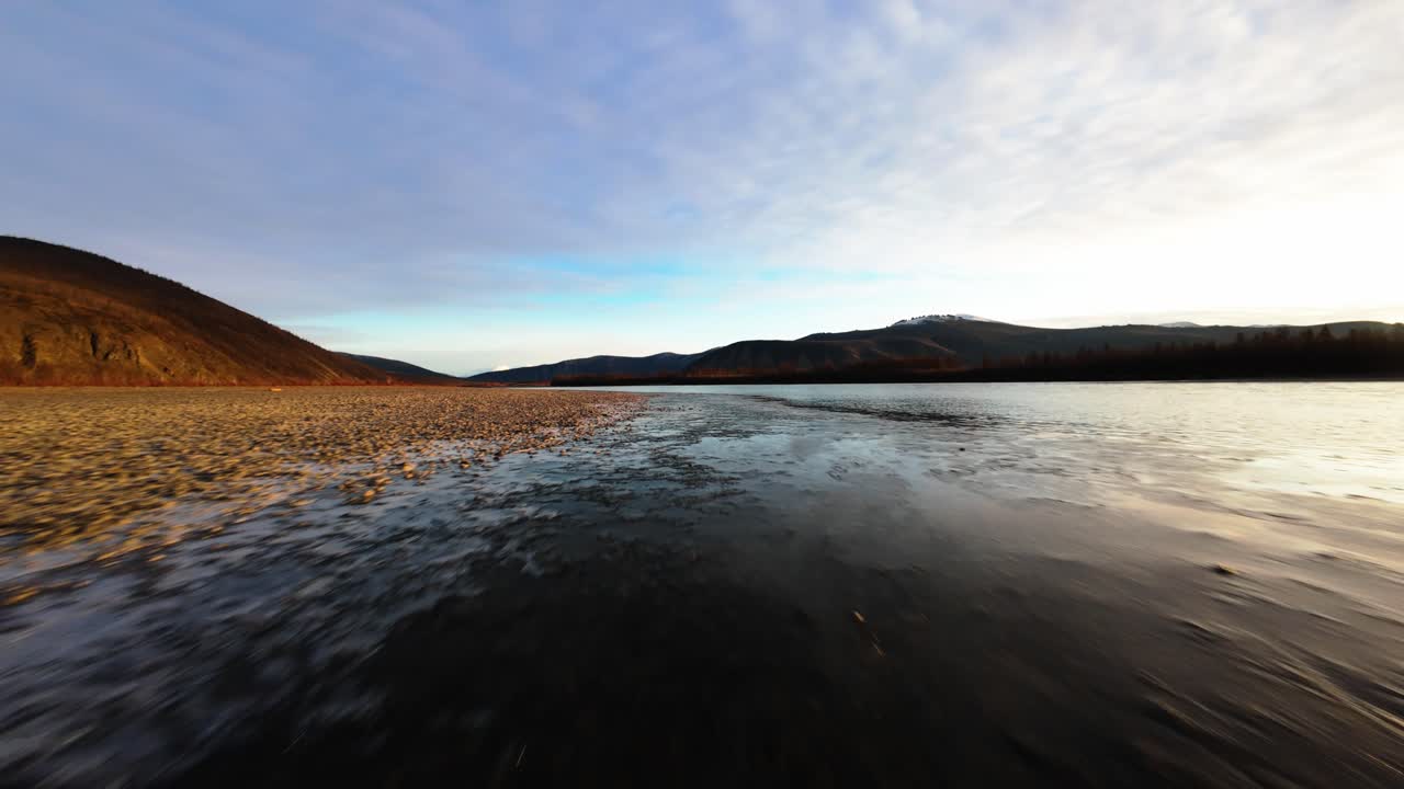 Experience the tranquility of Yakutia as a drone glides over stunning rivers and vast terrains at twilight. The enchanting beauty of this remote region unfolds in soft golden hues and serene waters.
