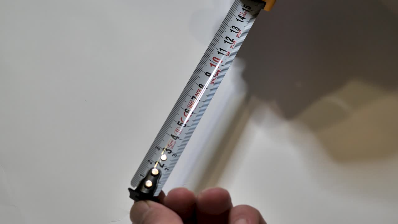 Tape measure. Hands pull the measuring yellow tape out. Roll of measuring tape. Scene G.