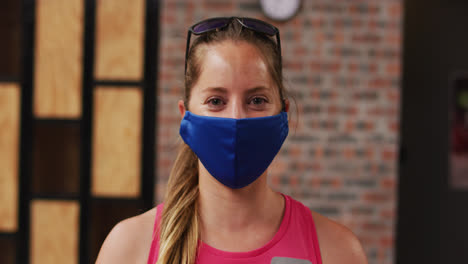 Portrait-of-caucasian-woman-wearing-face-mask-with-sunglasses-on-her-head-smiling