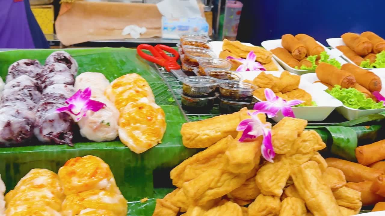 A vibrant display of Thai fried snacks, spring rolls, and skewered delights garnished with orchids.