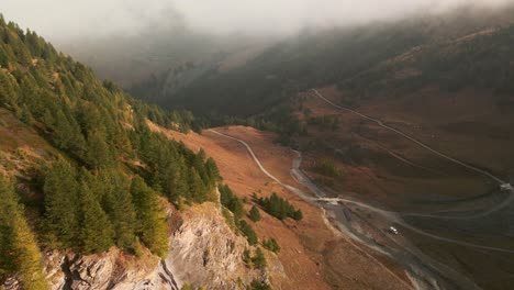 Grüne-Pinien-Im-Tal-Mit-Weißem-Lieferwagen,-Der-Während-Des-Nebligen-Sonnenaufgangs-In-Valle-Argentera,-Piemont,-Italien,-In-Der-Nähe-Des-Flussufers-Geparkt-Wurde