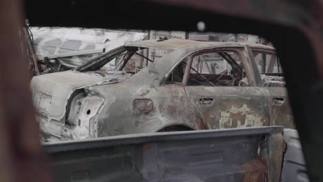 vista de un sedán muy dañado por el fuego a través de otra ventana de camión - vehículo destruido en un incendio forestal - 4k