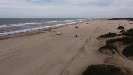 isolated 4x4 car driving along desert beach, mar de las pampas in argentina