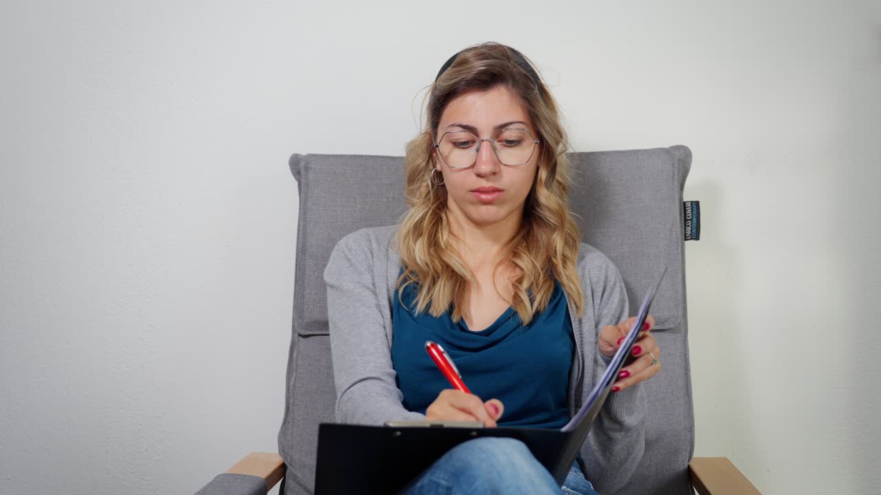 Young woman writing notes while seated, looking focused and slightly pensive