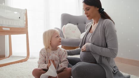 caucasian woman in advanced pregnancy browsing ultrasound scan with her elementary daughter.