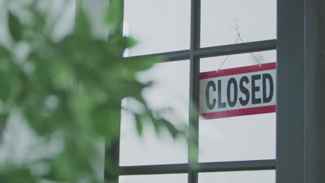 a hanging sign in a window that indicates the business is open until it is flipped over to show closed