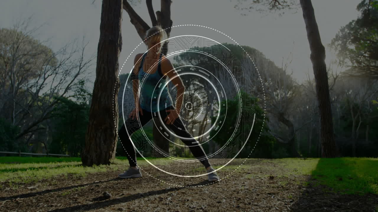 Woman performing wide side lunge in wooded park, showing circular digital HUD fitness overlay