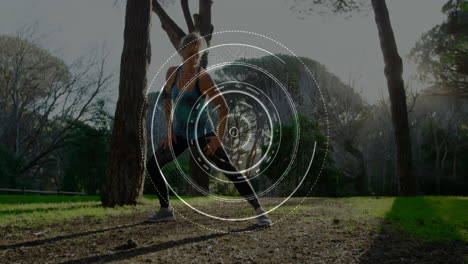 woman performing wide side lunge in wooded park, showing circular digital hud fitness overlay