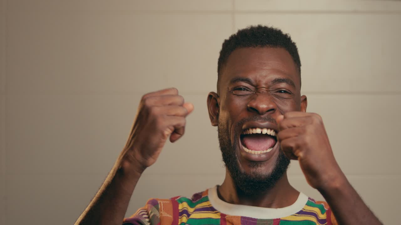 Primo piano di uomo afroamericano che indossa una camicia in tessuto Kente ed esprime successo