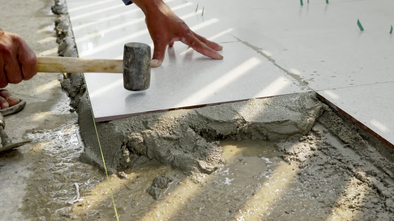 Esta imagem retrata o processo manual de assentamento de lajotas de concreto em um canteiro de obras.