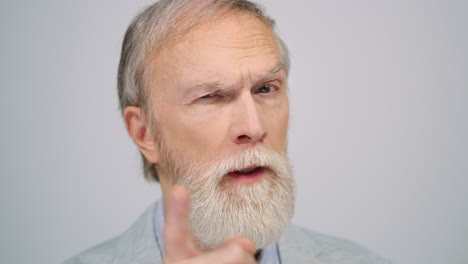 Old-man-wagging-finger-in-studio.-Serious-gentleman-looking-camera-indoors.