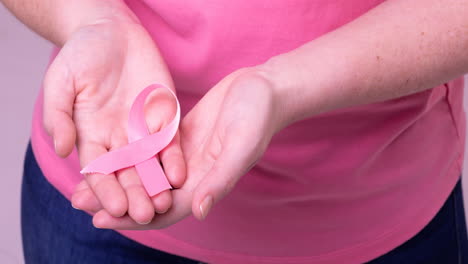 video of midsection of caucasian woman holding pink cancer awareness ribbon