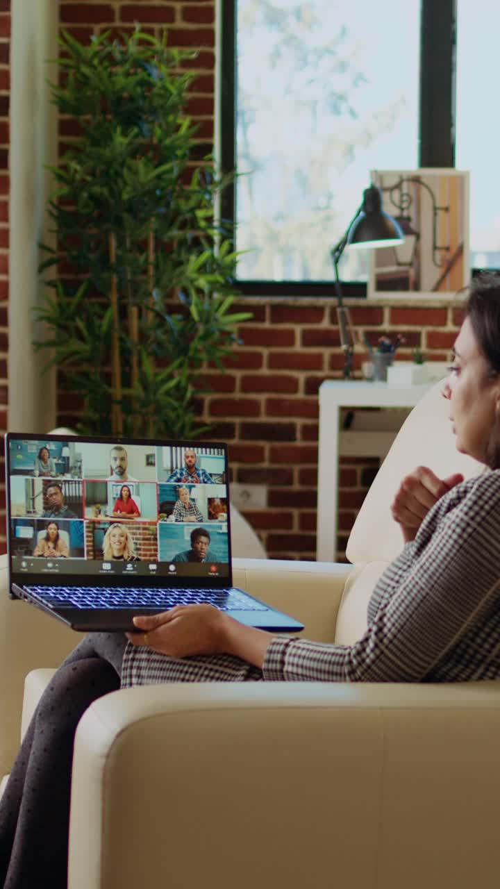 Vertical video Team leader in cozy apartment, chatting with coworkers during teleconference