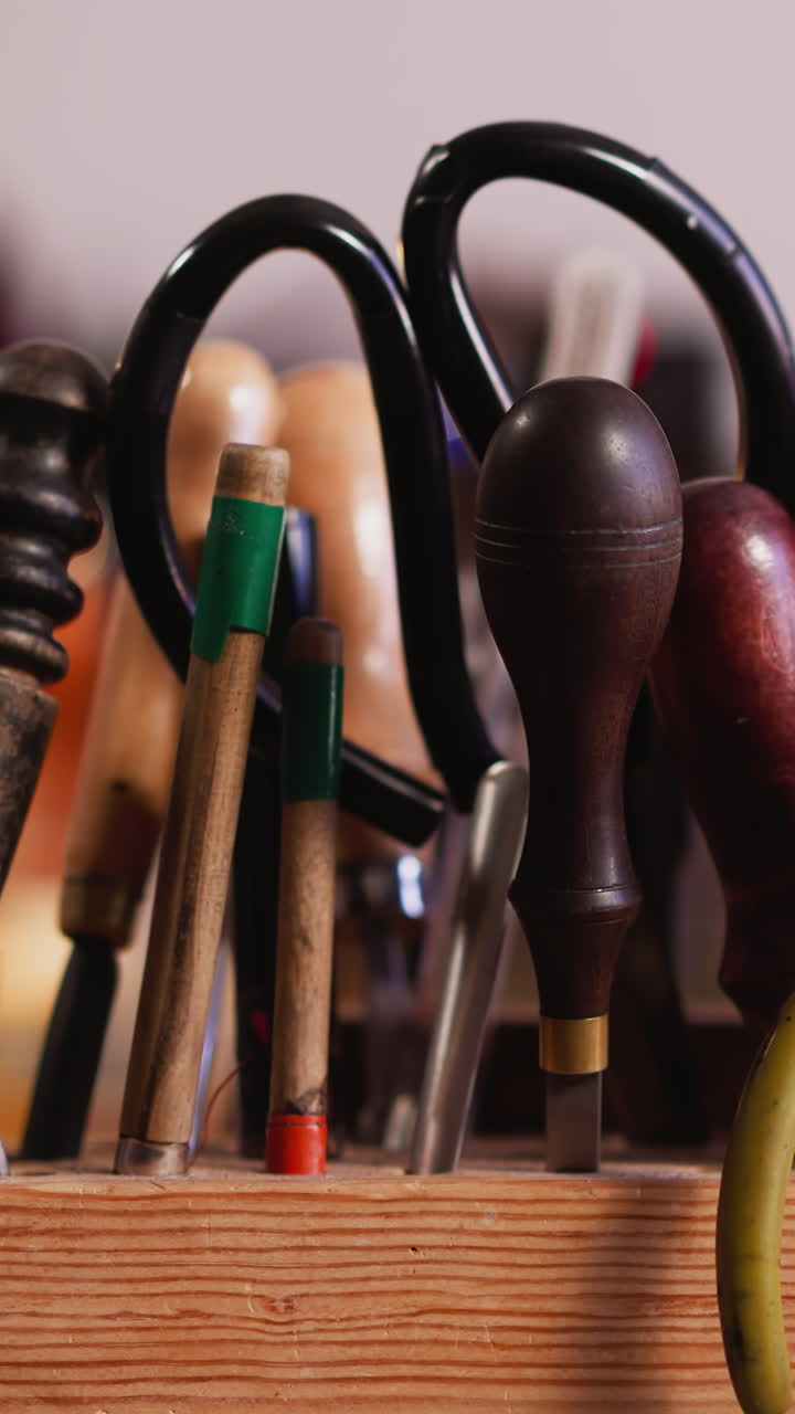 Wooden rack with kit of different leathersmith tools on workbench closeup. Instruments of professional craftsman in workshop. Manual work supplies