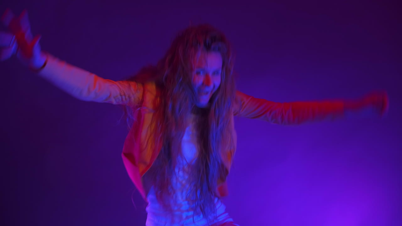 Funny unusual woman with long hair having fun smiling dancing in studio against blue background. Music dance concept