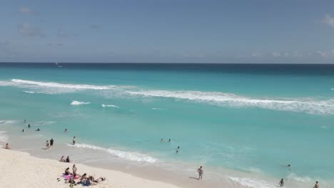 low aerial flyover: thatch parasols offer shade on cancun sand beach