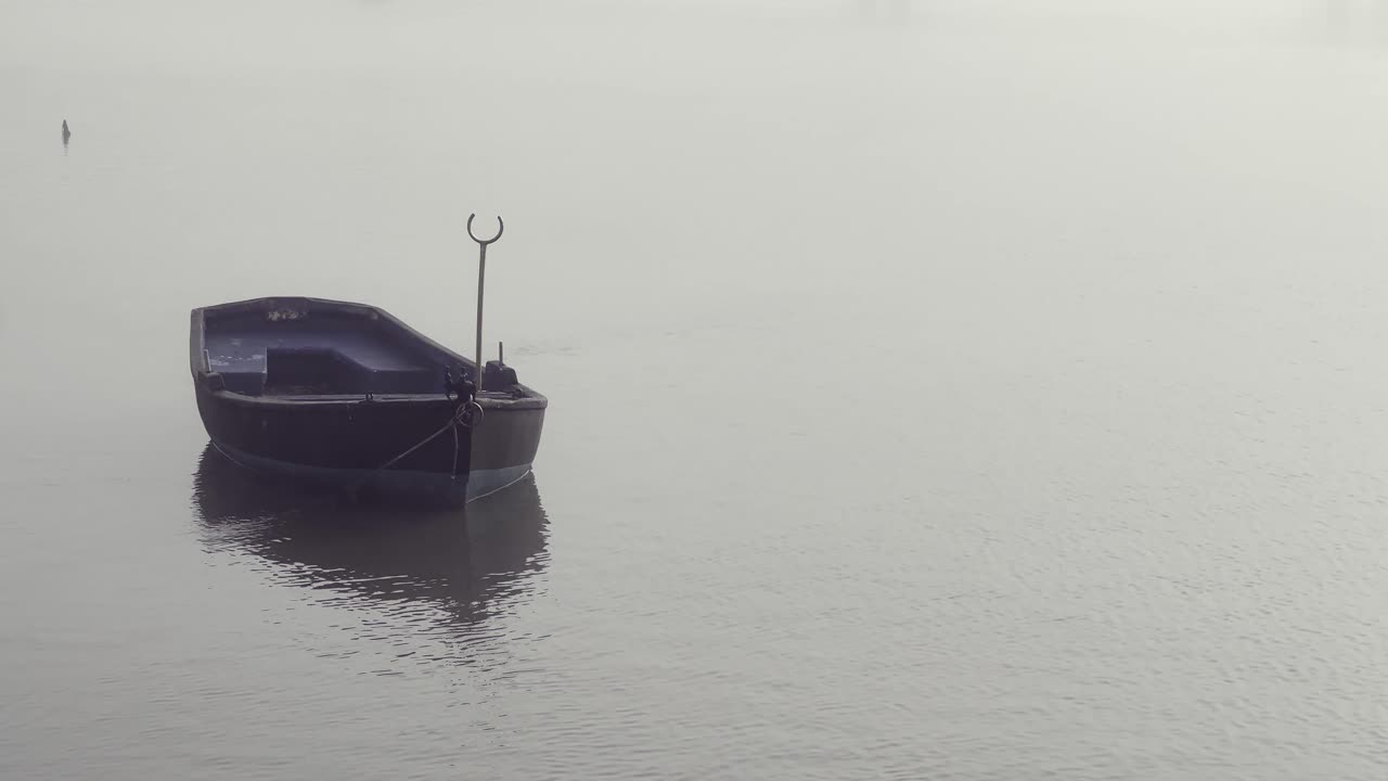 solitary boat stands at the pier in a foggy sea with a seagull flying by