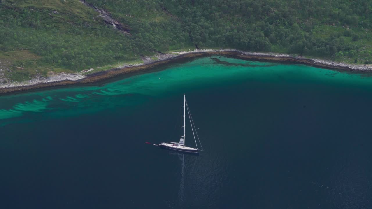 Luftfoto af båd, der ligger for anker i det blå hav med roligt vand i Norge