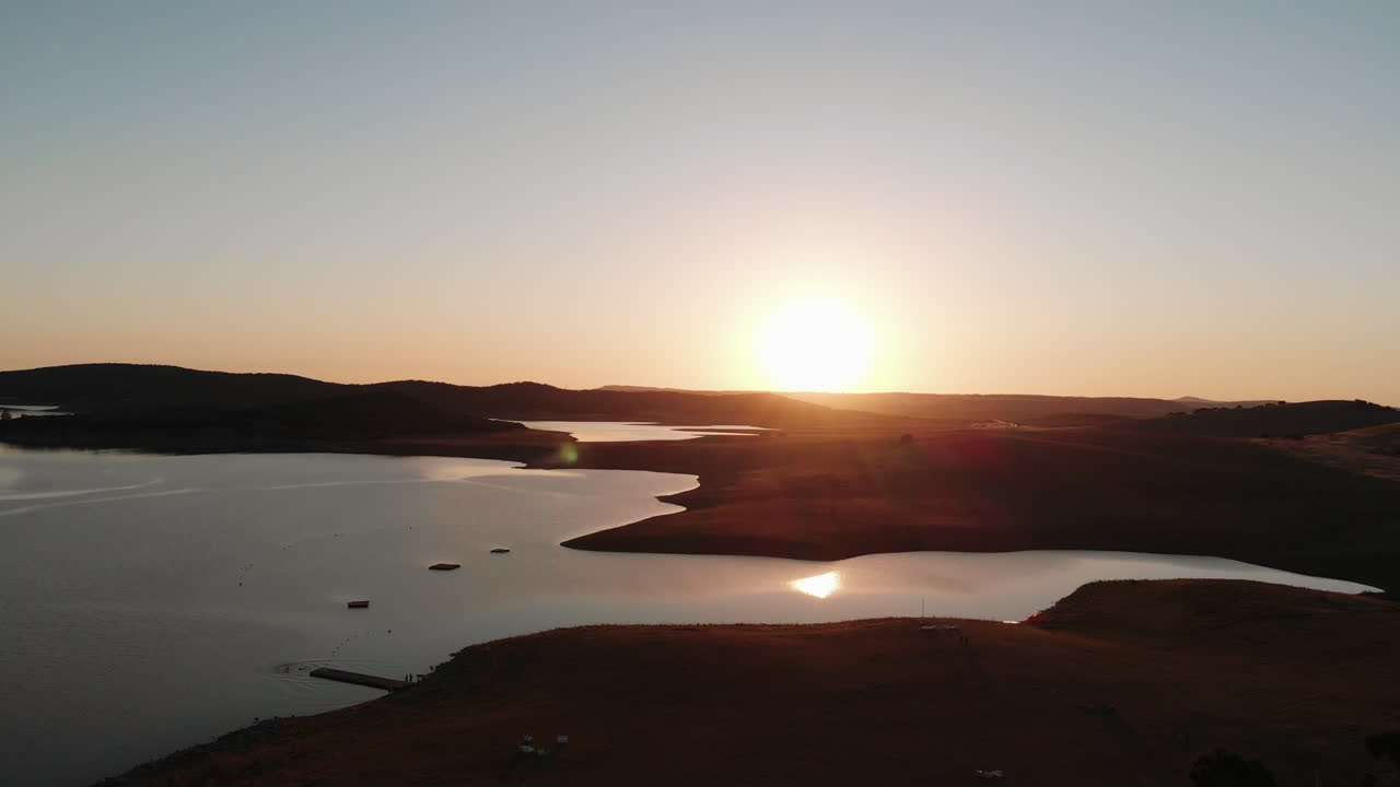 Silhueta de Colinas Áridas Cercando o Lago Wakana Sob um Pôr do Sol - Imagem Aérea com Movimento de Recuo e Inclinação para Baixo