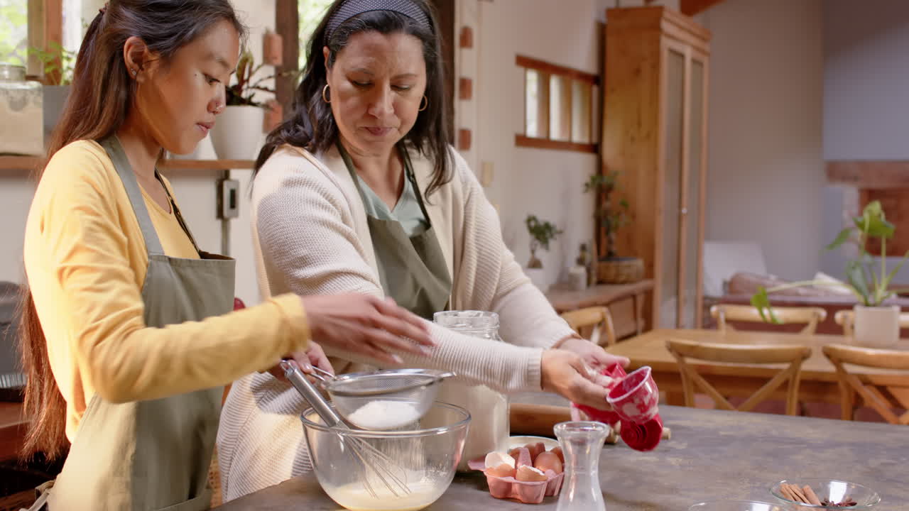 Multiracial young woman and grandmother in cozy kitchen together, at home