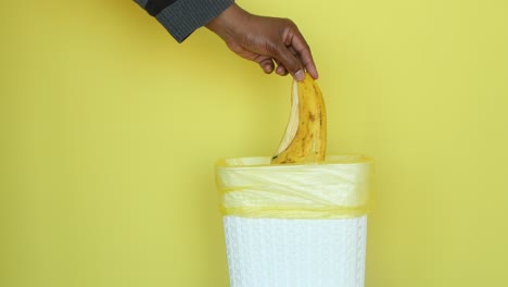 a person throwing a banana peel into a trash can