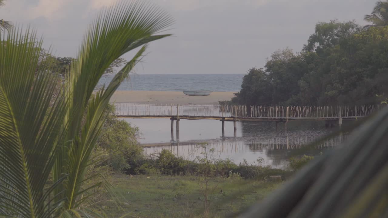 Wooden bridge over the Rekawa lagoon in Tangalle, beach background, Sri Lanka