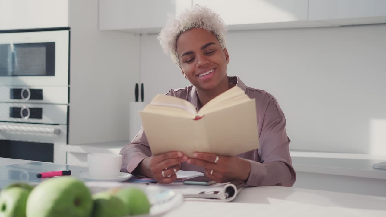 Young african american woman smiling reading favorite book during lunch break