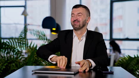 smiling good-looking bearded man opens his laptop. man changes in face when he can't open his computer. blurred backdrop.